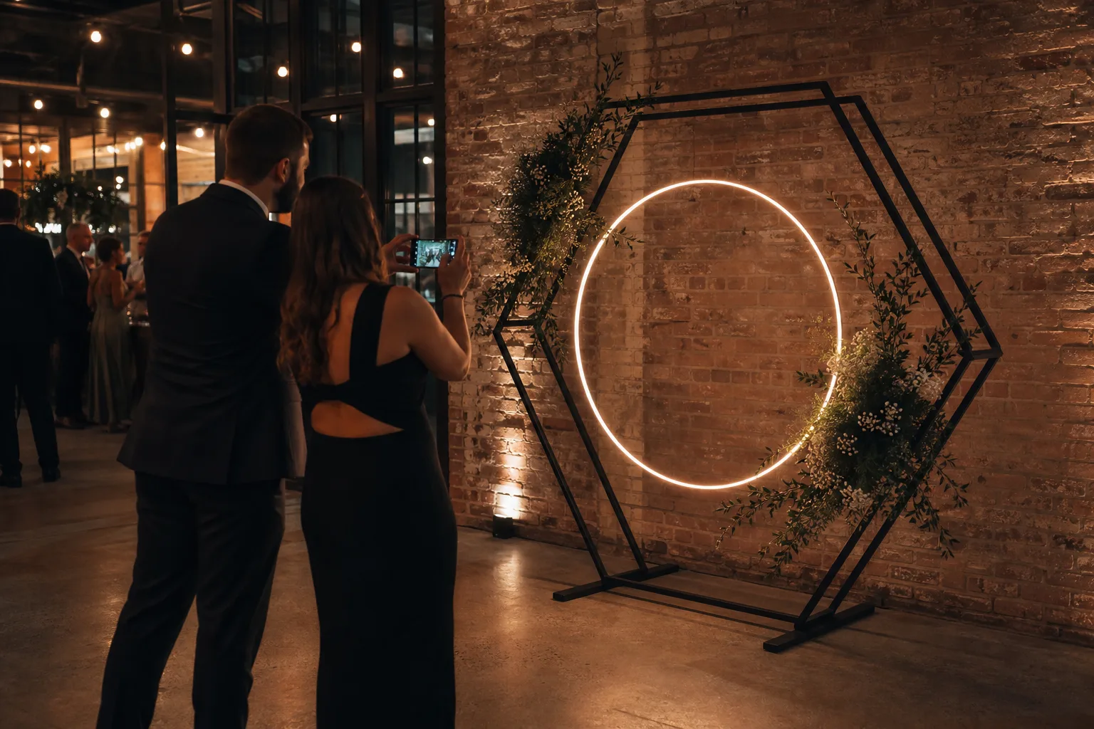 Matte-black double-line hexagonal arch with warm circular light at an evening reception