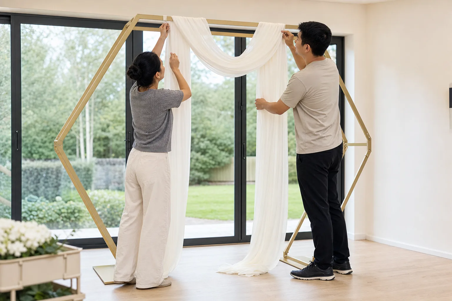 Two installers balancing ivory chiffon across the top of a gold hexagonal arch